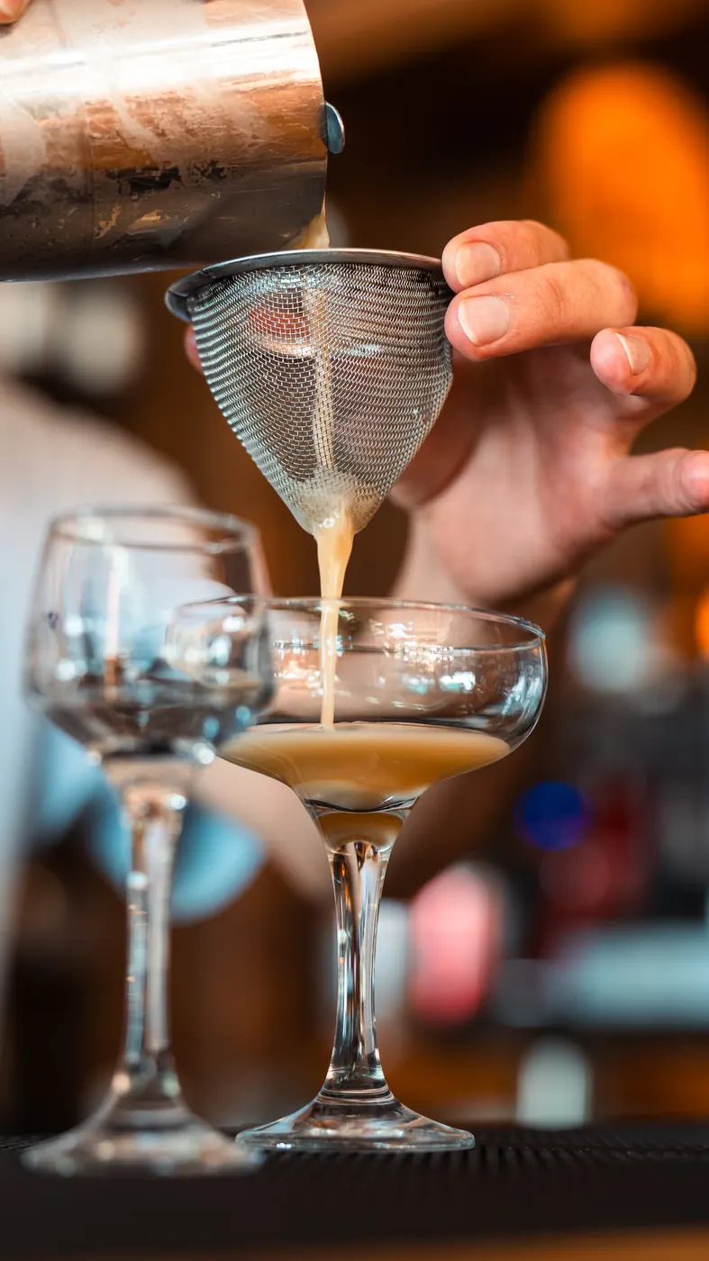 Cocktail being strained into a coupe glass