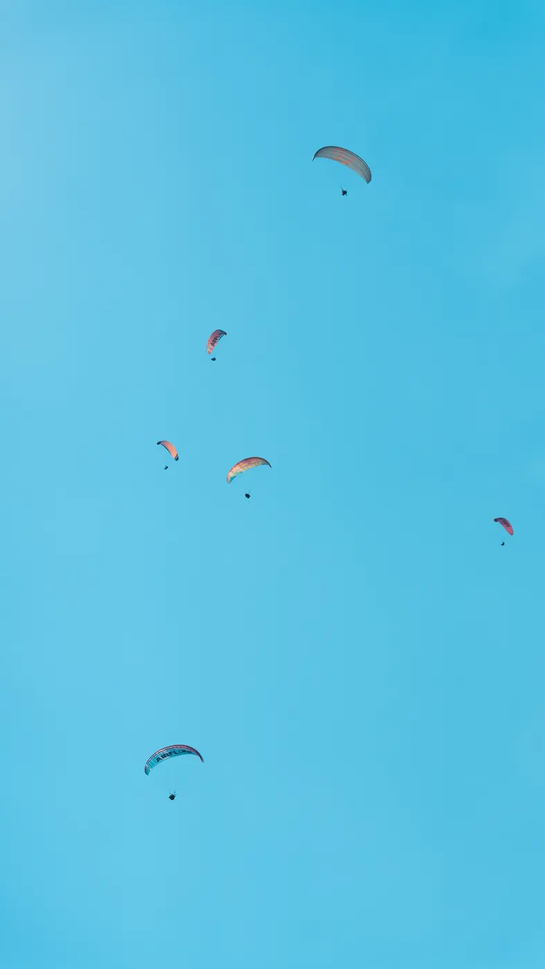 Paragliders drifting across a blue sky