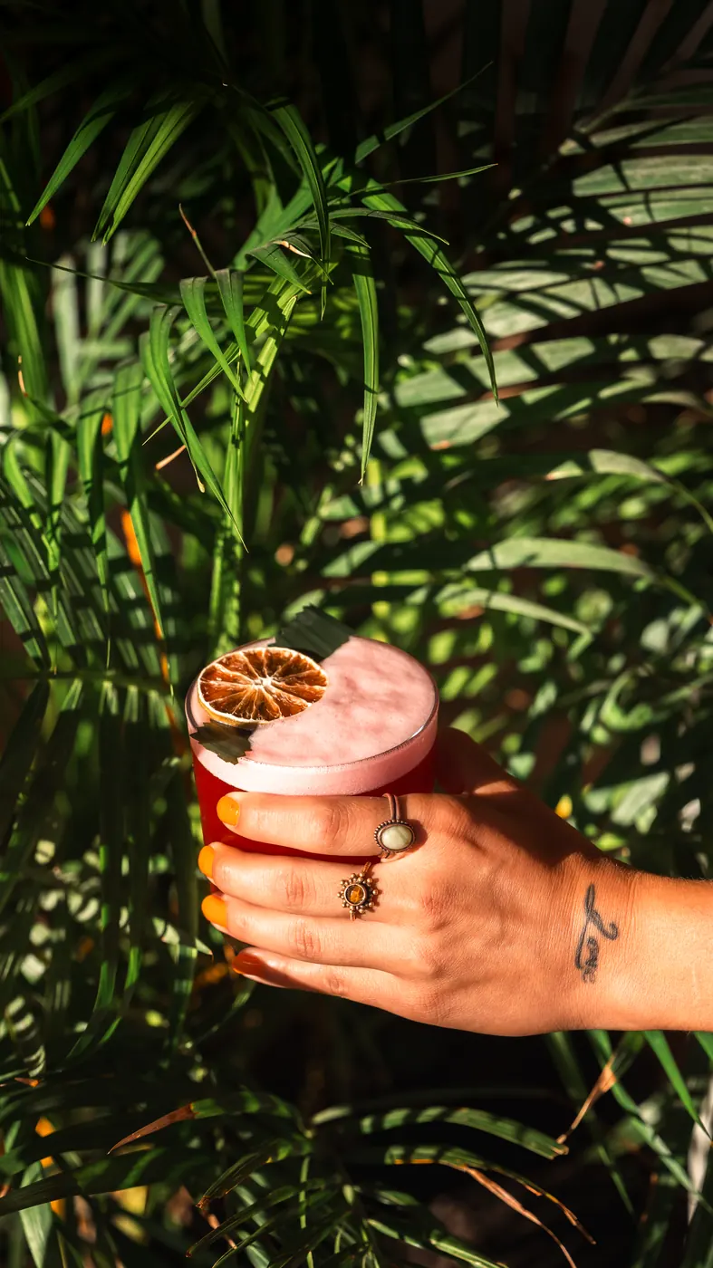 A pink cocktail among palm leaves