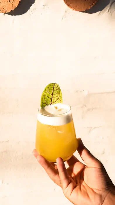 A yellow cocktail held in hand